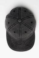 Six-Panel Cotton Baseball Cap with Cursive Artwork on the Brim in Vintage Black - flat lay product view