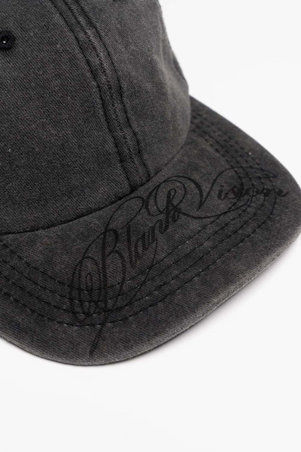 Six-Panel Cotton Baseball Cap with Cursive Artwork on the Brim in Vintage Black - product detail close-up