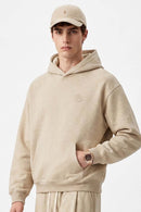 Relaxed Pullover Hoodie with Embroidered Emblem in Apricot - three-quarter front modeled view