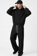 Relaxed Pullover Hoodie with Embroidered Emblem in Black - full-length front modeled view