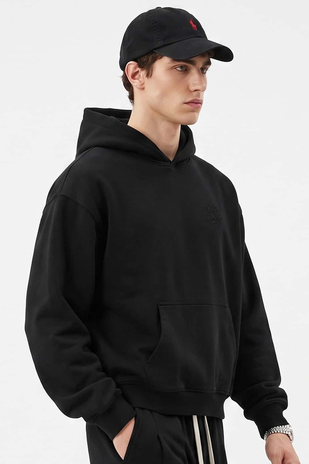 Relaxed Pullover Hoodie with Embroidered Emblem in Black - three-quarter front modeled view