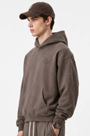 Relaxed Pullover Hoodie with Embroidered Emblem in Coffee - three-quarter front modeled view