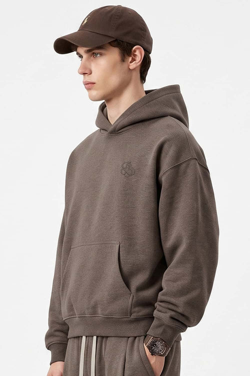 Relaxed Pullover Hoodie with Embroidered Emblem in Coffee - three-quarter front modeled view