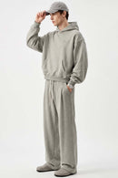 Relaxed Pullover Hoodie with Embroidered Emblem in Oat Gray - full-length front modeled view