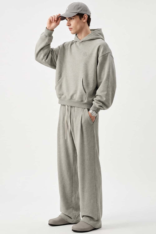 Relaxed Pullover Hoodie with Embroidered Emblem in Oat Gray - full-length front modeled view
