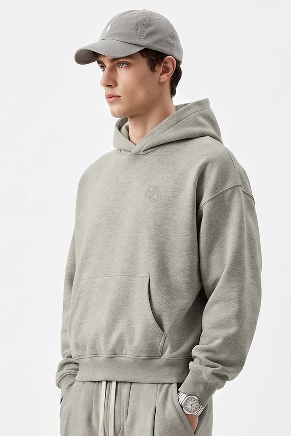 Relaxed Pullover Hoodie with Embroidered Emblem in Oat Gray - three-quarter front modeled view